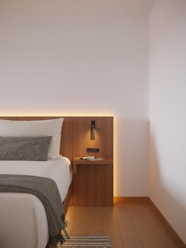 A minimalistic bedroom corner with a bed, a wooden nightstand, wall-mounted lamp, and soft lighting.